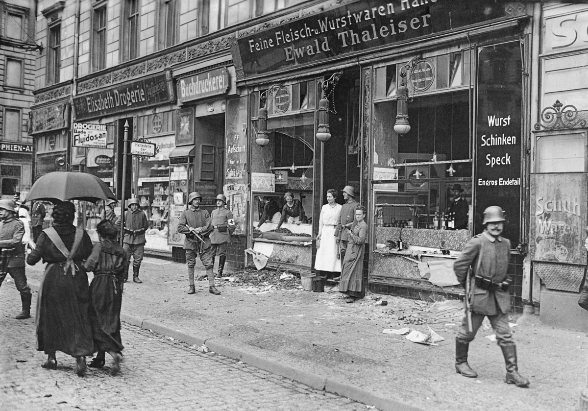 Armed soldiers stand guard outside a delicatessen that has been plundered. Invalidenstrasse, Berlin, 1918.